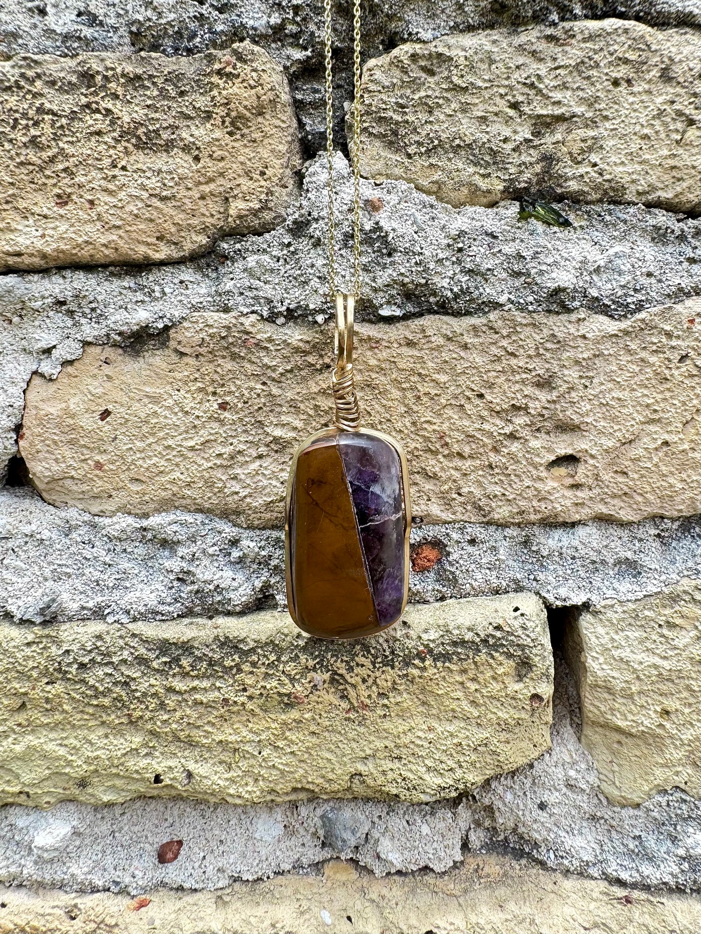 Pendant necklace with a stone pendant on a stone wall background