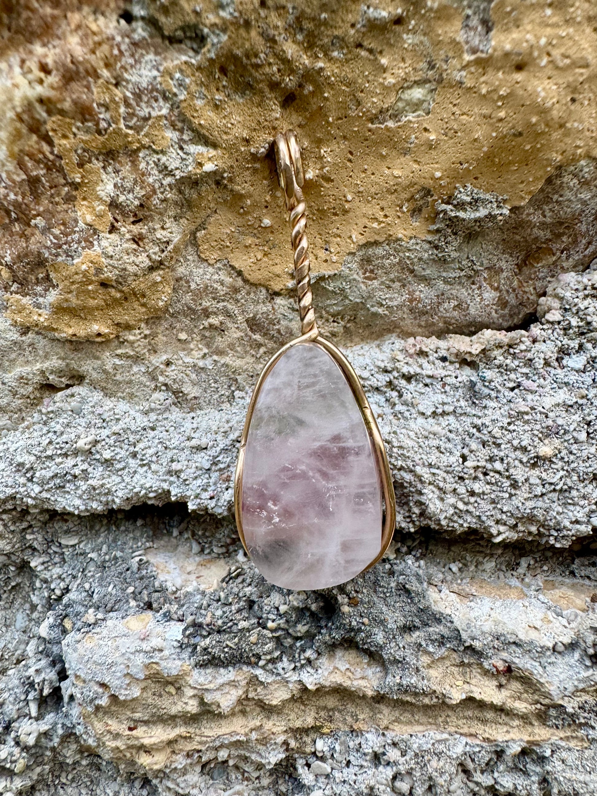 Crystal pendant with gold setting on a stone background