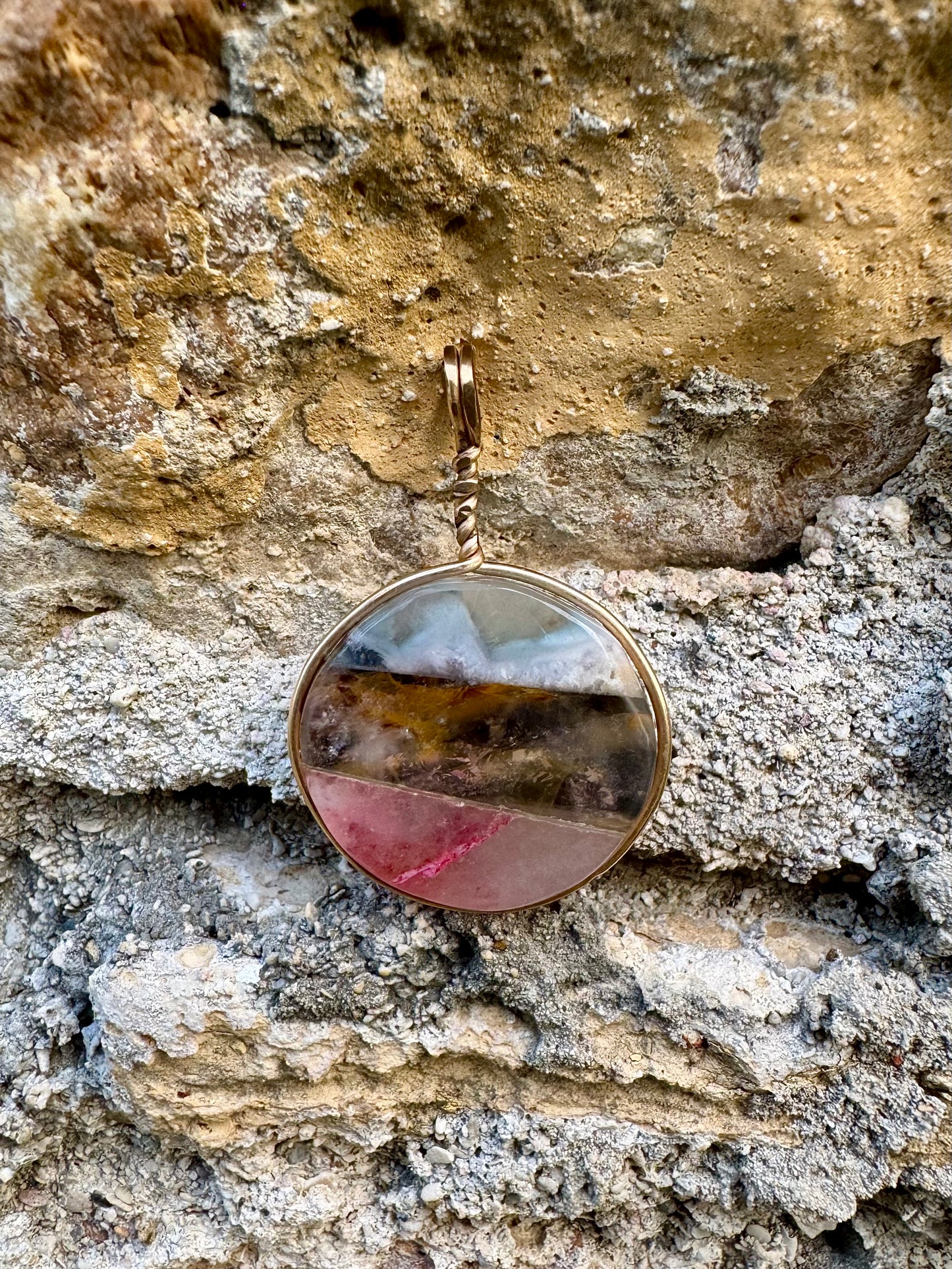 Round pendant with a multicolored stone on a stone wall background