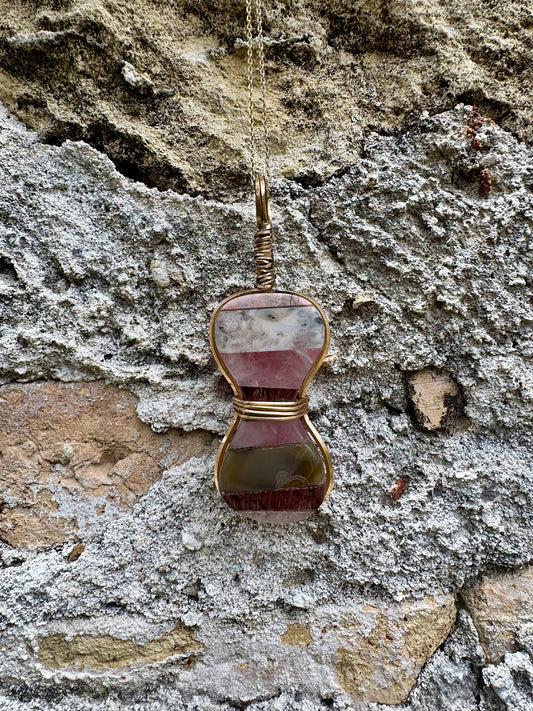Gold-wrapped hourglass semi-precious gemstone pendant on stone background