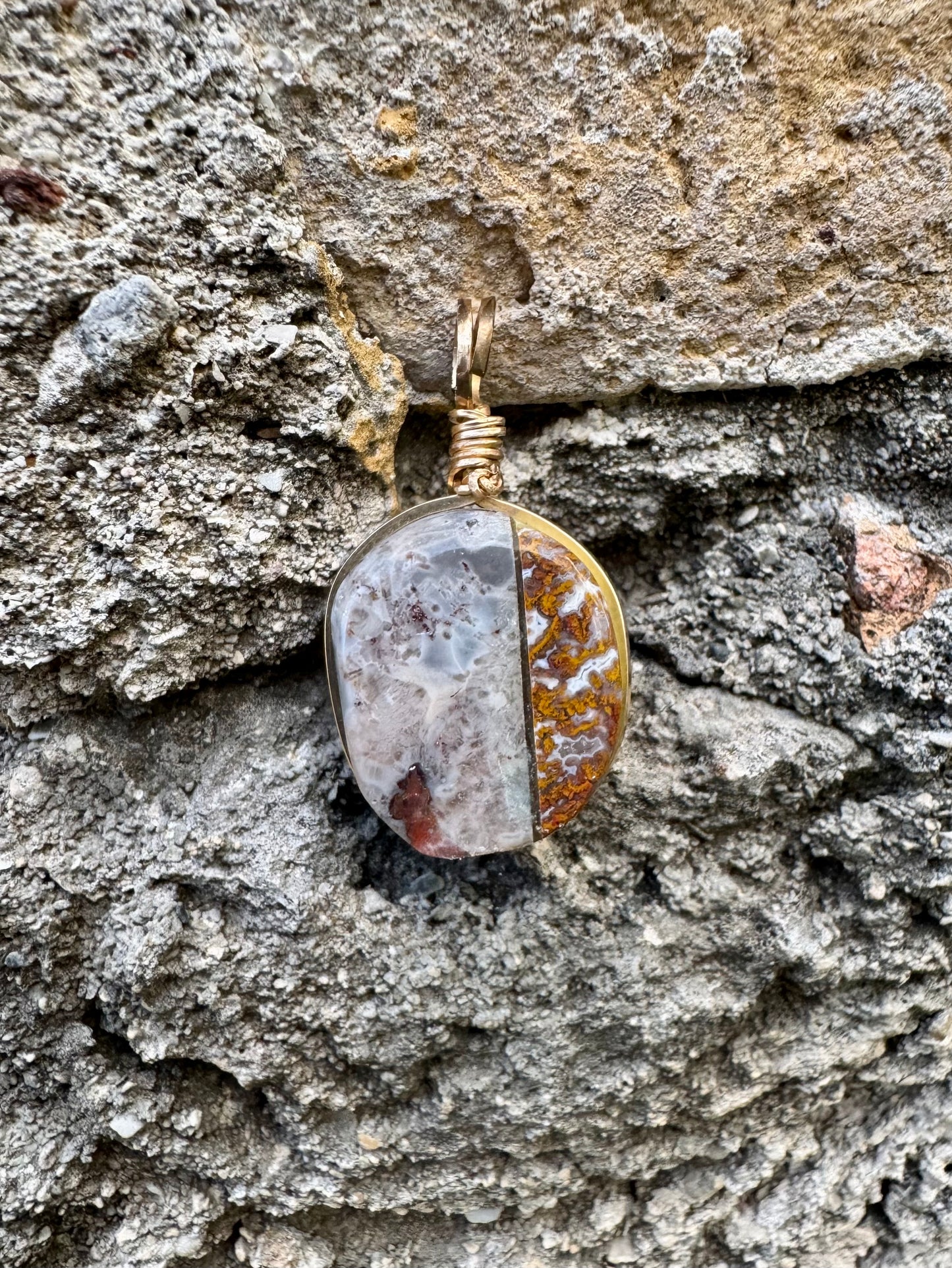 Pendant with a natural stone design hanging on a textured stone wall