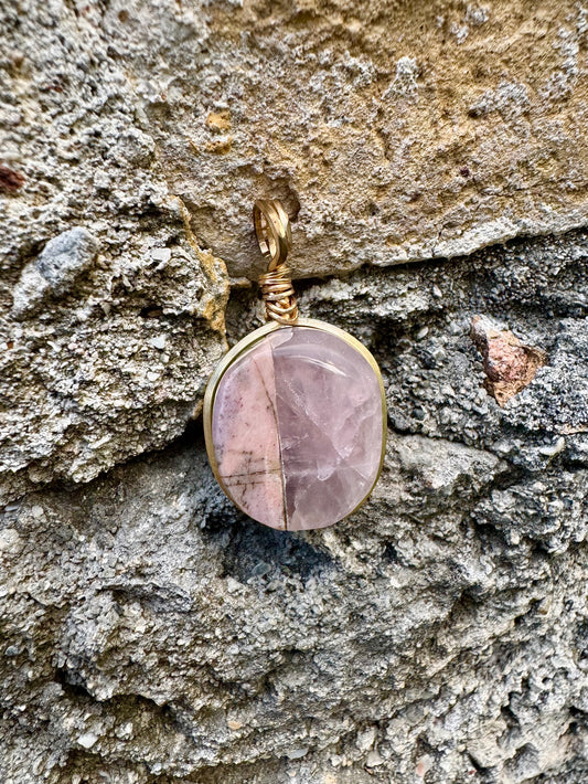 Pink stone pendant on a textured stone surface